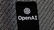 FILE. The OpenAI logo appears on a mobile phone in front of a computer screen with random binary data. Boston. 9 March 2023.