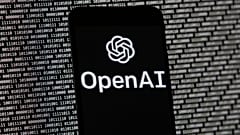 FILE. The OpenAI logo appears on a mobile phone in front of a computer screen with random binary data. Boston. 9 March 2023. 