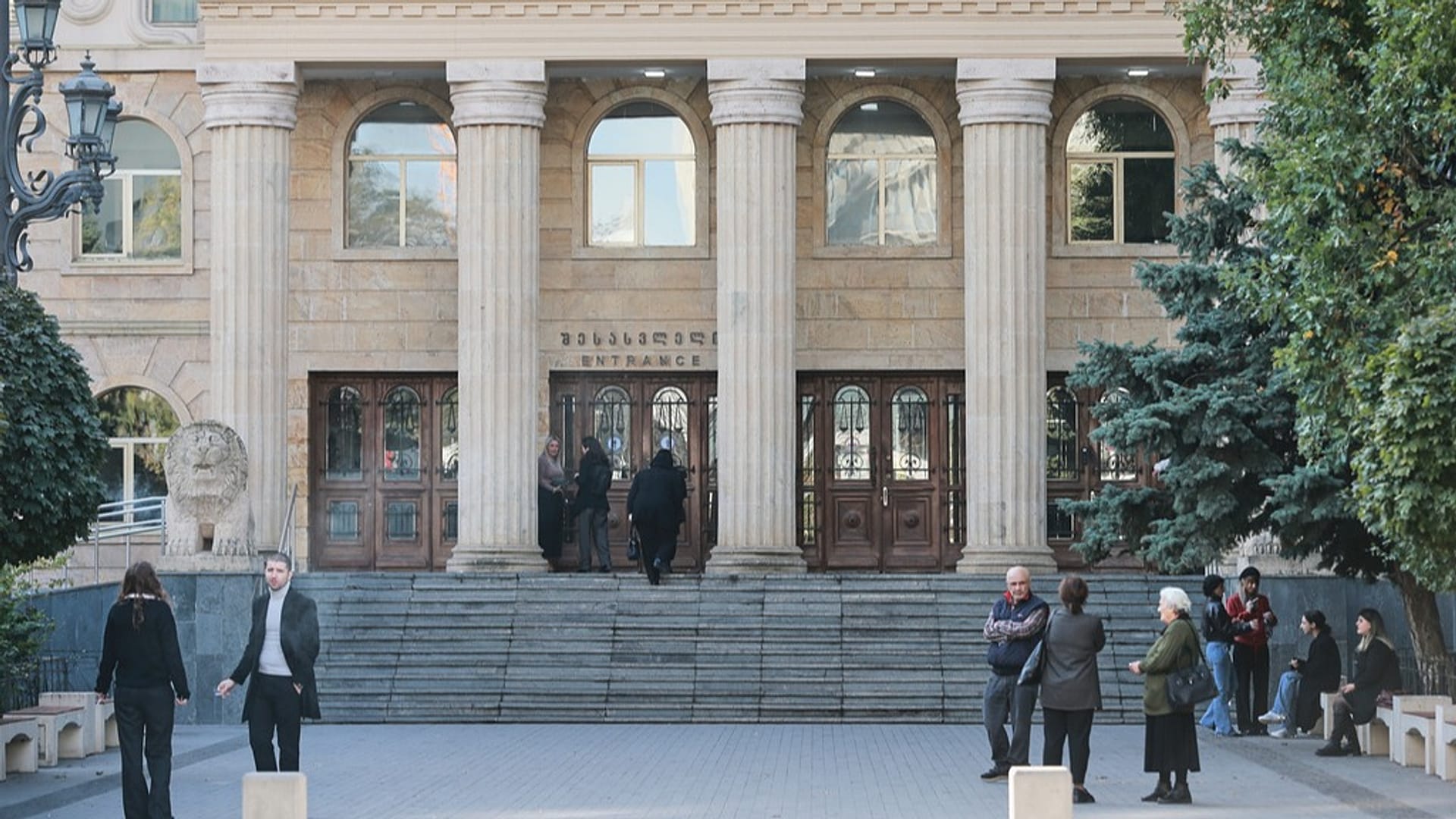 ليان كينيدي، في الخلفية إلى اليسار، تقف عند المدخل أثناء وصولها لحضور جلسة المحكمة في تبليسي، جورجيا، الثلاثاء، 28 أكتوبر/تشرين الأول 2025.