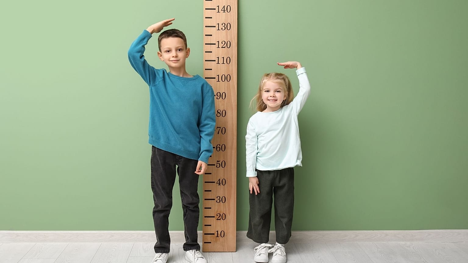 صبي وفتاة يقفان إلى جانب مقياس للطول.