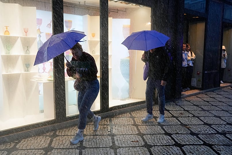 Ludzie szukają schronienia podczas ulewnych opadów deszczu w centrum Lizbony, we wtorek, 28 października 2025 roku.