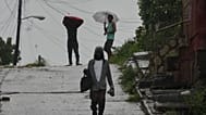People walk under the rain before the arrival of Hurricane Melissa in Santiago de Cuba, Tuesday, Oct. 28, 2025. (AP Photo/Ramón Espinosa)