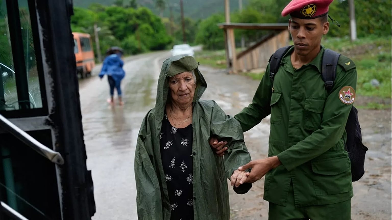 Un soldado ayuda a una mujer a evacuar antes de la llegada del huracán Melissa en Canizo, una comunidad de Santiago de Cuba, el martes 28 de octubre de 2025.