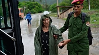 Un soldado ayuda a una mujer a evacuar antes de la llegada del huracán Melissa en Canizo, una comunidad de Santiago de Cuba, el martes 28 de octubre de 2025. 