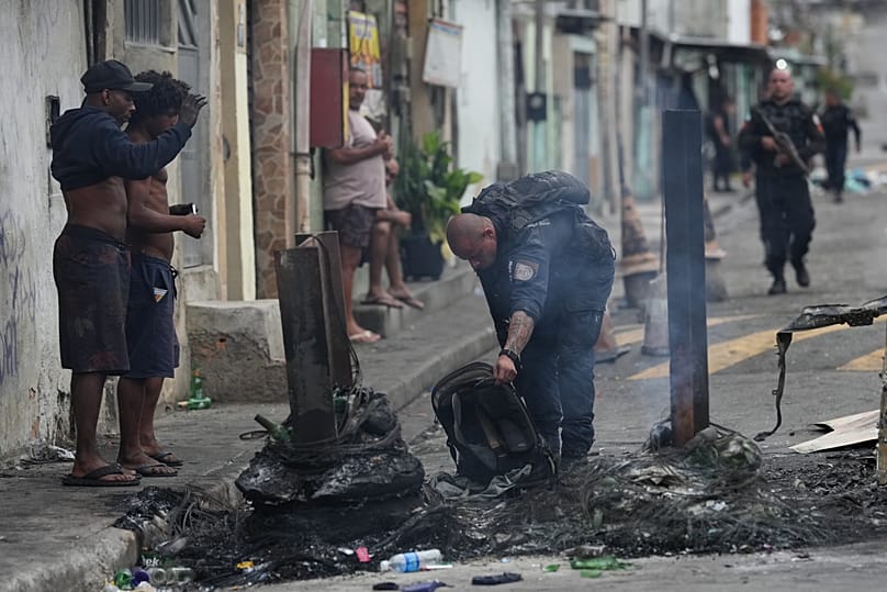 Un policier soulève un sac à dos qui fait partie d'une barricade routière érigée par des trafiquants de drogue présumés lors d'une opération policière dans la favela Complexo.
