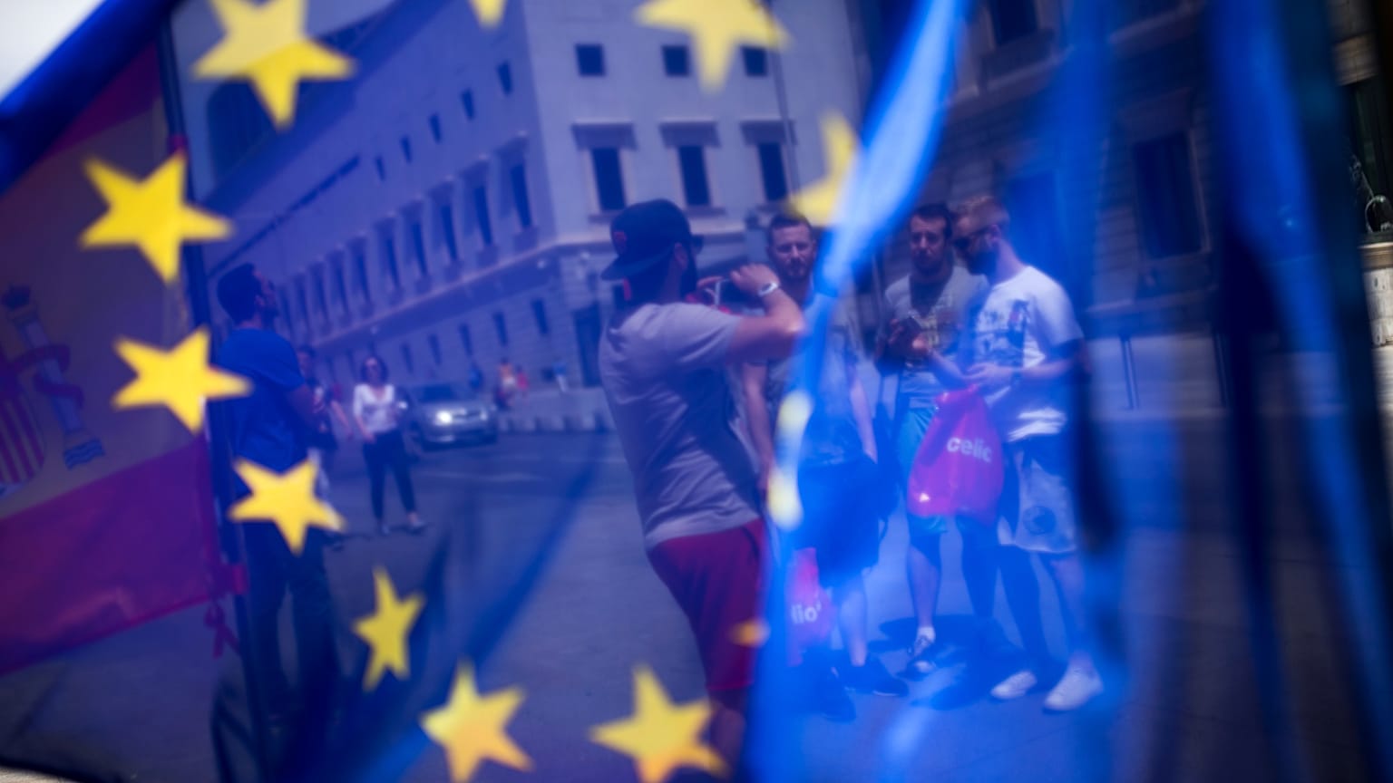 En esta foto del viernes 24 de junio de 2016, se ve a un grupo de turistas posando para una fotografía frente al Parlamento a través de la bandera de la UE en Madrid, España.
