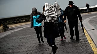 Una mujer intenta resguardarse de la lluvia y el fuerte viento con su paraguas en el "Paseo Nuevo", en San Sebastián, norte de España, el domingo 5 de febrero de 2017.