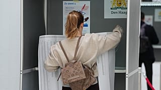 Une femme tient une feuille listant tous les candidats lors des élections législatives à La Haye, aux Pays-Bas, le mercredi 29 octobre 2025