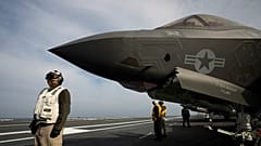 DOSSIER - Des marins de l'US Navy à côté d'un avion de combat F-35 sur le pont d'un porte-avions, le 30 mai 2024.