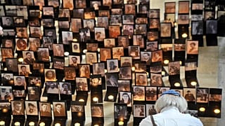 رجل يقف أمام صور وشموع معروضة في معرض بعنوان "وجوه الضحايا"، الذي يُحيي ذكرى ضحايا الهولوكوست في مركز هولوكوست التذكاري في بودابست، المجر،