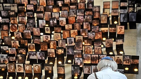 رجل يقف أمام صور وشموع معروضة في معرض بعنوان "وجوه الضحايا"، الذي يُحيي ذكرى ضحايا الهولوكوست في مركز هولوكوست التذكاري في بودابست، المجر،