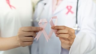 طبيبة وسيدة تحملان شريطين زهريين رمزًا للتضامن مع مريضات سرطان الثدي