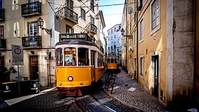 Elétricos circulam pelas ruas estreitas do bairro de Alfama, em Lisboa, Portugal