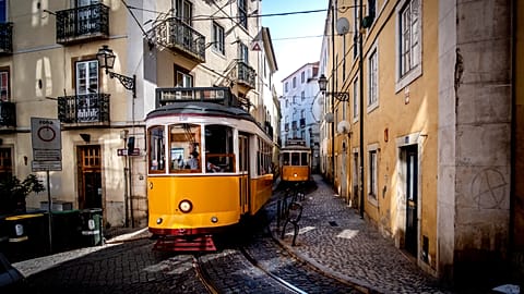 Trams make their way through the narrow streets of the Alfama district in Lisbon.