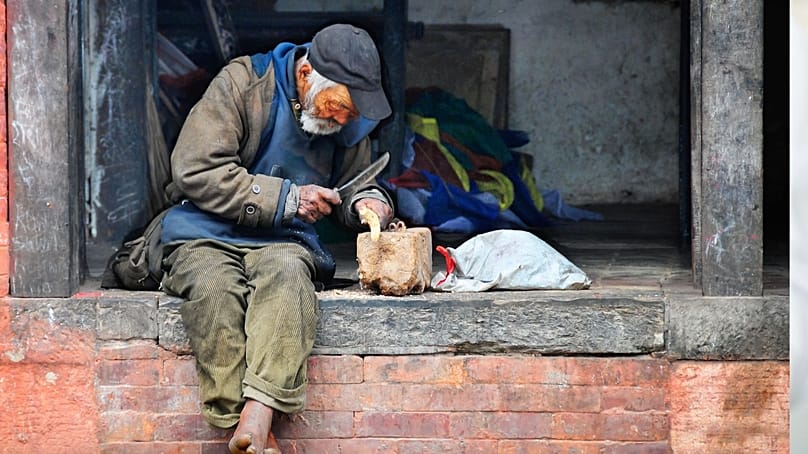 Starszy mężczyzna siedzi w progu domu.