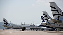 Самолет компании Aegean Airlines подъезжает к терминалу, в то время как другие самолеты стоят на стоянке в международном аэропорту Элефтериос Венизелос в Афинах, 31 марта 2020 года.