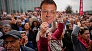 امرأة ترفع قناعاً عليه صورة رئيس بلدية إسطنبول المعارض المسجون، أكرم إمام أوغلو، خلال تجمع لدعمه أثناء مثوله أمام محكمة تشاغلايان في إسطنبول، تركيا، يوم الأحد 26 أكتوبر/تشرين 