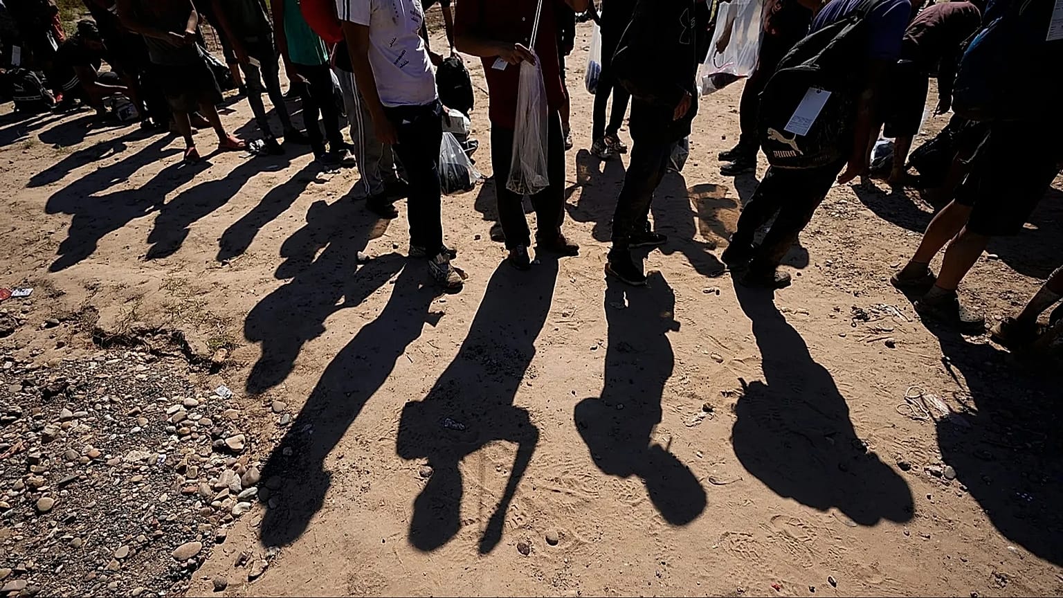 Migrants wait to be processed by the US Customs and Border Patrol after they entered the US from Mexico, 19 October, 2023