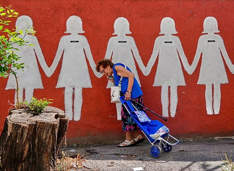 Bir kadın, Roma'da aile içi şiddet kurbanlarını anan bir duvar resminin önünden geçiyor, 20 Temmuz 2025. (AP Fotoğrafı/Gregorio Borgia)