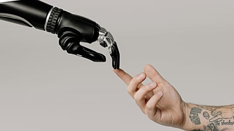 Image of a robotic arm and a human arm approaching each other in an allegory between the closeness of science and humanity.