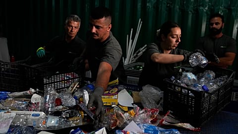 Members of a recycling plant separate waste at a sorting bench on the island of Tilos in the Aegean Sea, southeastern Greece, 2022