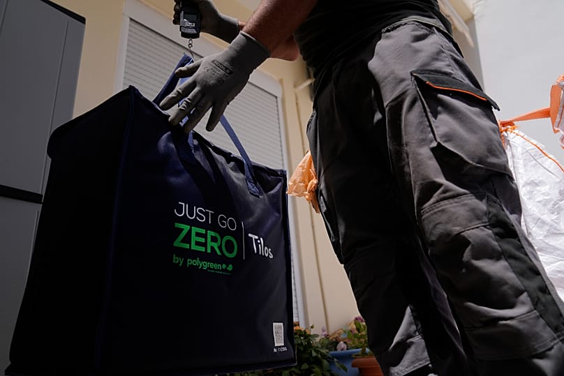 Μέλος του συνεργείου συλλογής απορριμμάτων χρησιμοποιεί φορητή ζυγαριά για να ζυγίσει τα σκουπίδια για ανακύκλωση στο νησί της Τήλου στο Αιγαίο Πέλαγος