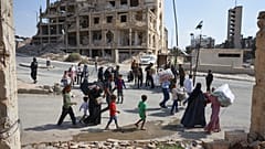 سكان يسيرون عبر حاجز لقوات الأمن وهم يغادرون حي الشيخ مقصود والأحرفية في حلب ، سوريا ، الثلاثاء ، أكتوبر. في 7 ديسمبر 2025 