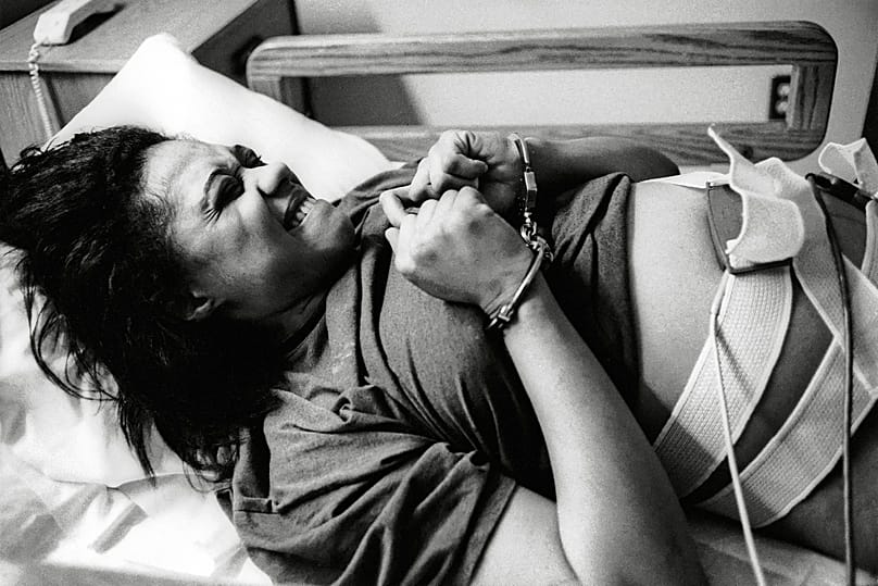 Handcuffed, pregnant inmate writhes in pain during gynecological examination, moments before she gave birth by cesarean. Providence City Hospital, Anchorage, Alaska, 1993 