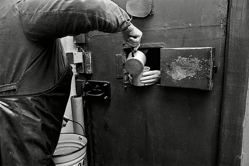 Inmate serves boiled water instead of tea or coffee to prisoner in solitary confinement. Perm penal colony for women, Perm, Russia, 1990