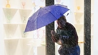 Uma mulher segura o guarda-chuva contra o vento durante uma forte chuva, no centro de Lisboa, terça-feira, 28 de outubro de 2025.
