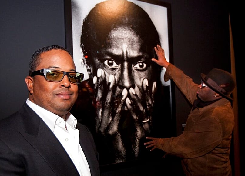 إيرين ديفيس ، نجل الراحل جريت مايلز ديفيس ، يقف أمام صورة لوالده في معاينة معرض" نريد مايلز"