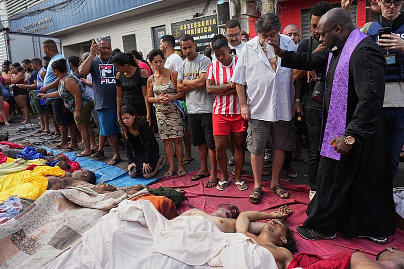Um padre abençoa os corpos das pessoas mortas no dia anterior durante uma operação policial contra o Comando Vermelho. 