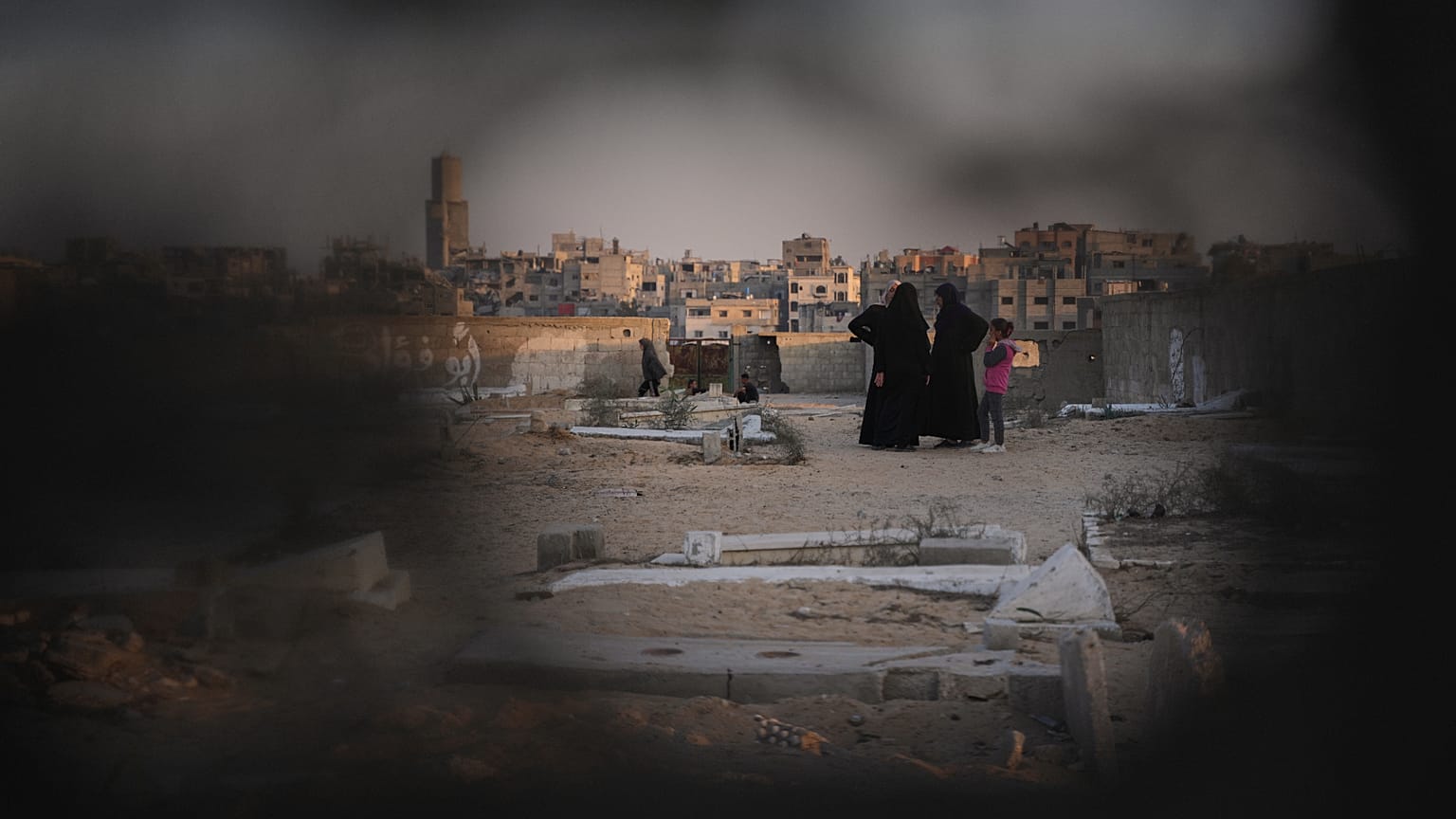 تقف نساء فلسطينيات في مقبرة في خان يونس، حيث أُقيم مخيّم مؤقّت للنازحين، في جنوب قطاع غزة، الجمعة، 31 أكتوبر 2025. 