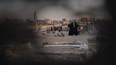 تقف نساء فلسطينيات في مقبرة في خان يونس، حيث أُقيم مخيّم مؤقّت للنازحين، في جنوب قطاع غزة، الجمعة، 31 أكتوبر 2025. 