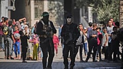 A Hamász milicistái őrködnek, miközben elrabolt izraeli túszok maradványait keresik egyiptomi munkások a Gázai övezetben lévő Nuszeiratban 2025. október 28-án 