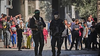 A Hamász milicistái őrködnek, miközben elrabolt izraeli túszok maradványait keresik egyiptomi munkások a Gázai övezetben lévő Nuszeiratban 2025. október 28-án 