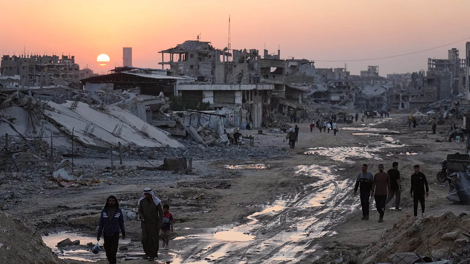 فلسطينيون يسيرون بين مبانٍ مدمّرة في خان يونس، جنوب قطاع غزة، الأحد، 2 تشرين الثاني/نوفمبر 2025. 