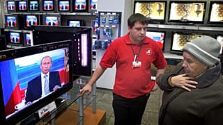 Una donna in un negozio di elettrodomestici di Mosca mentre viene trasmessa un'apparizione del Presidente russo Vladimir Putin il 18 ottobre 2007.