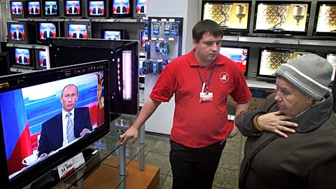 A woman in a Moscow appliance shop while an appearance by Russian President Vladimir Putin is being broadcast on 18 October 2007.