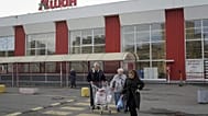 Des clients sortent après avoir fait leurs achats dans un magasin du distributeur français Auchan à Saint-Pétersbourg, en Russie, le jeudi 24 octobre 2024.