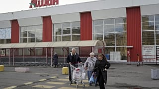 Des clients sortent après avoir fait leurs achats dans un magasin du distributeur français Auchan à Saint-Pétersbourg, en Russie, le jeudi 24 octobre 2024.