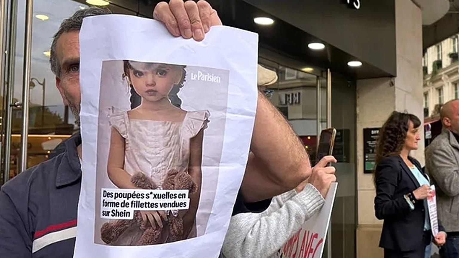 Un manifestante sostiene una imagen de una muñeca sexual infantil.