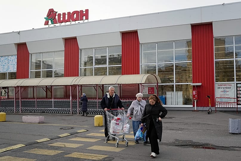 Customers walk after shopping in a store of the French retailer Auchan in St. Petersburg, 24 October, 2024