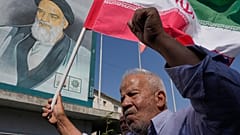 إيراني يحمل علم بلاده أمام صورة مؤسس الثورة الراحل الخميني خلال مظاهرة مناهضة لإسرائيل بطهران، إيران، الجمعة 10 أكتوبر 2025