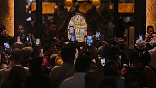  أشخاص يحملون أجهزة محمولة أمام قناع الدفن الذهبي للملك توت عنخ آمون خلال اليوم الأول للزوار بعد الافتتاح الرسمي للمتحف المصري الكبير في الجيزة، مصر، الثلاثاء 4 نوفمبر 2025. 