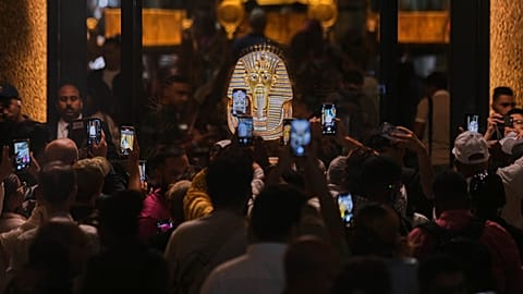  أشخاص يحملون أجهزة محمولة أمام قناع الدفن الذهبي للملك توت عنخ آمون خلال اليوم الأول للزوار بعد الافتتاح الرسمي للمتحف المصري الكبير في الجيزة، مصر، الثلاثاء 4 نوفمبر 2025. 