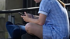 Sydney, am achten November 2024: Ein junges Mädchen sitzt auf einer Bank und nutzt ihr Handy.