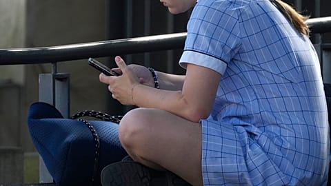 A young girl uses her phone while sitting on a bench in Sydney, Nov. 8, 2024.