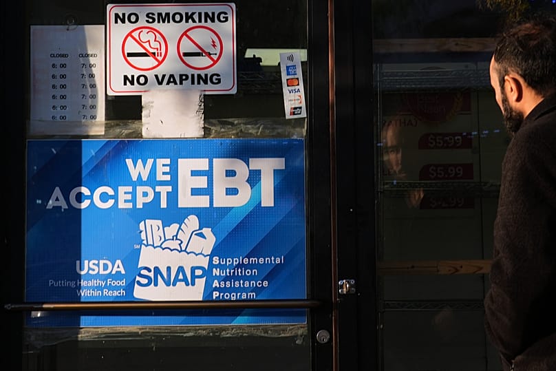 Um cliente entra numa padaria com um cartaz informativo "SNAP EBT" afixado na porta da frente em Chicago, 2 de novembro de 2025