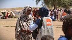 امرأة تتحدث مع أحد عمال الإغاثة في مخيم للنازحين لجأ إليه سكان مدينة الفاشر هربًا من القتال بين القوات الحكومية وقوات الدعم السريع